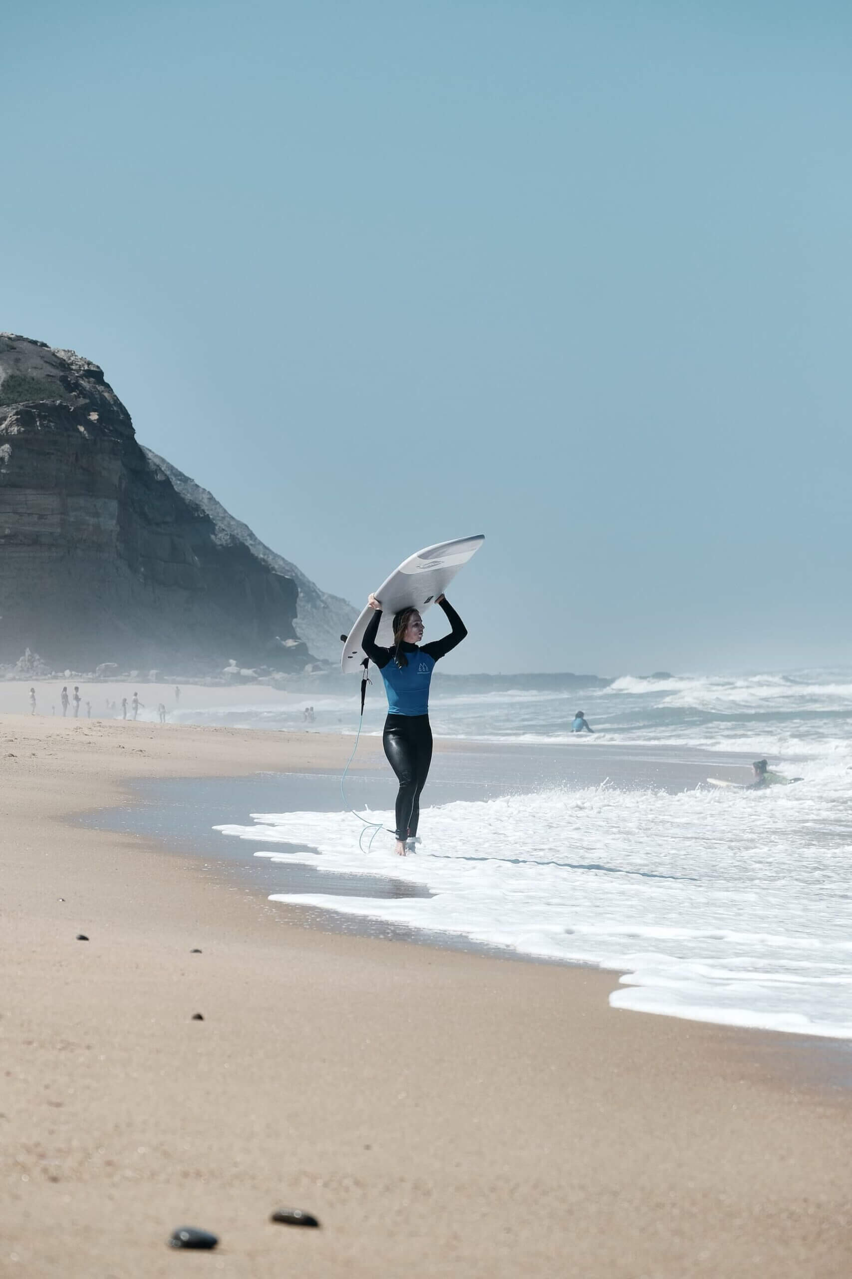 Surferin geht an der Wasserkante entlang